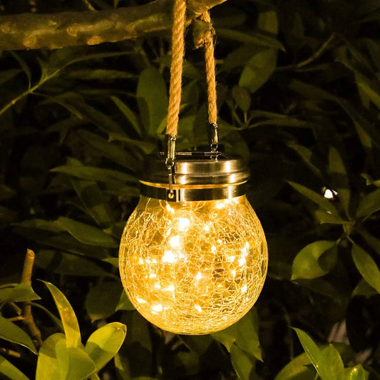 Solar-powered hanging light with crinkled glass design in a natural setting