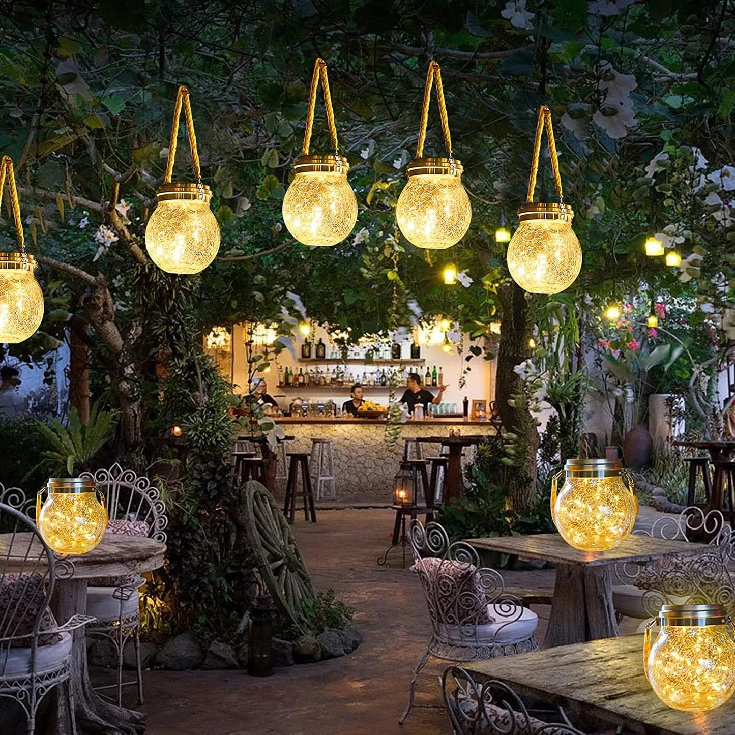 Outdoor setting with hanging lantern-like lights in a garden or patio area.