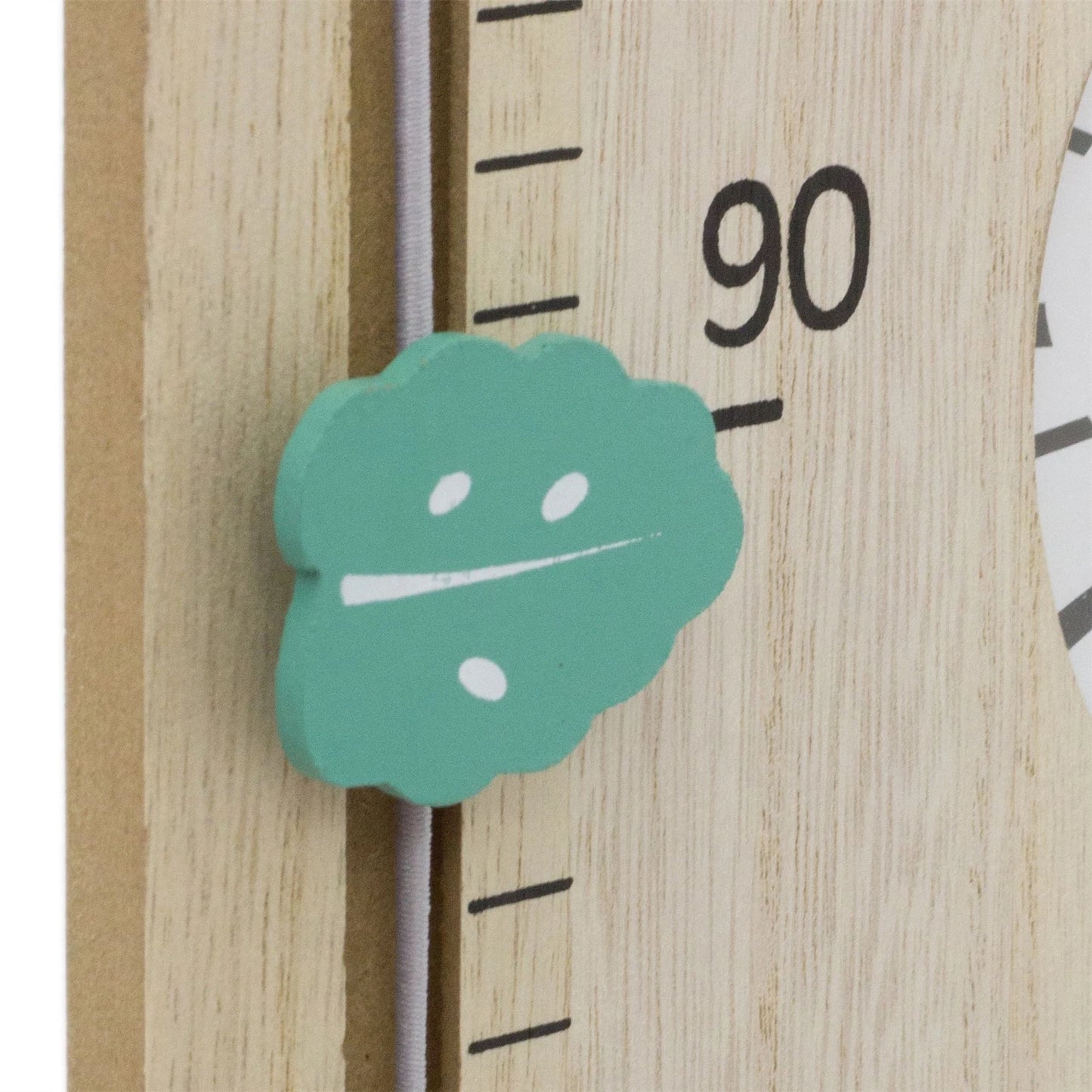 Teal leaf-shaped sticker on a wooden ruler with measurement markings