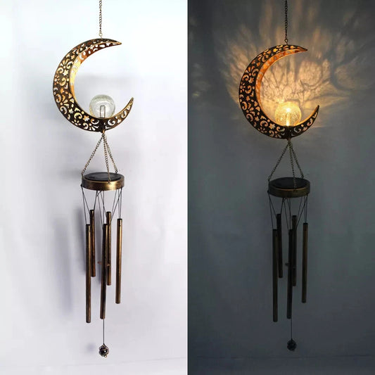 Decorative moon-shaped wind chime with hanging candles on a plain background
