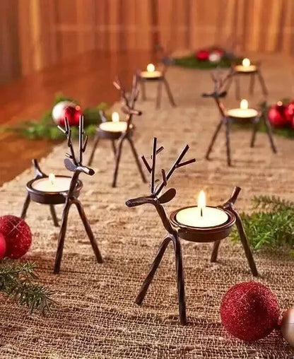 Decorative reindeer candle holders with candles on a textured surface with Christmas decorations.