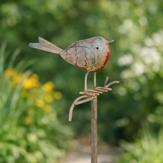 Metal bird sculpture on a stand with a blurred garden background