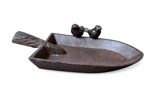 Cast iron dish shaped like a boat with two small figures on a white background