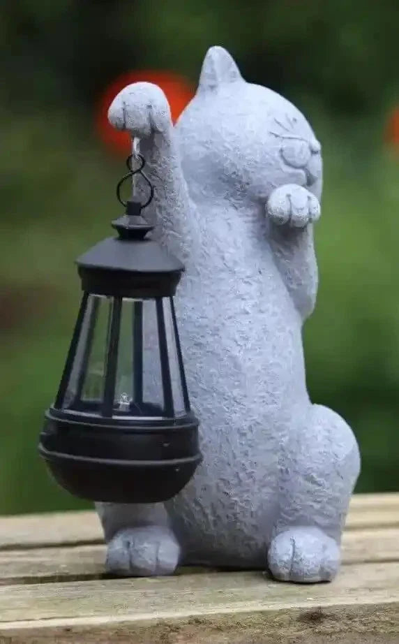 Cat-shaped decorative lantern on a wooden surface with a blurred green background