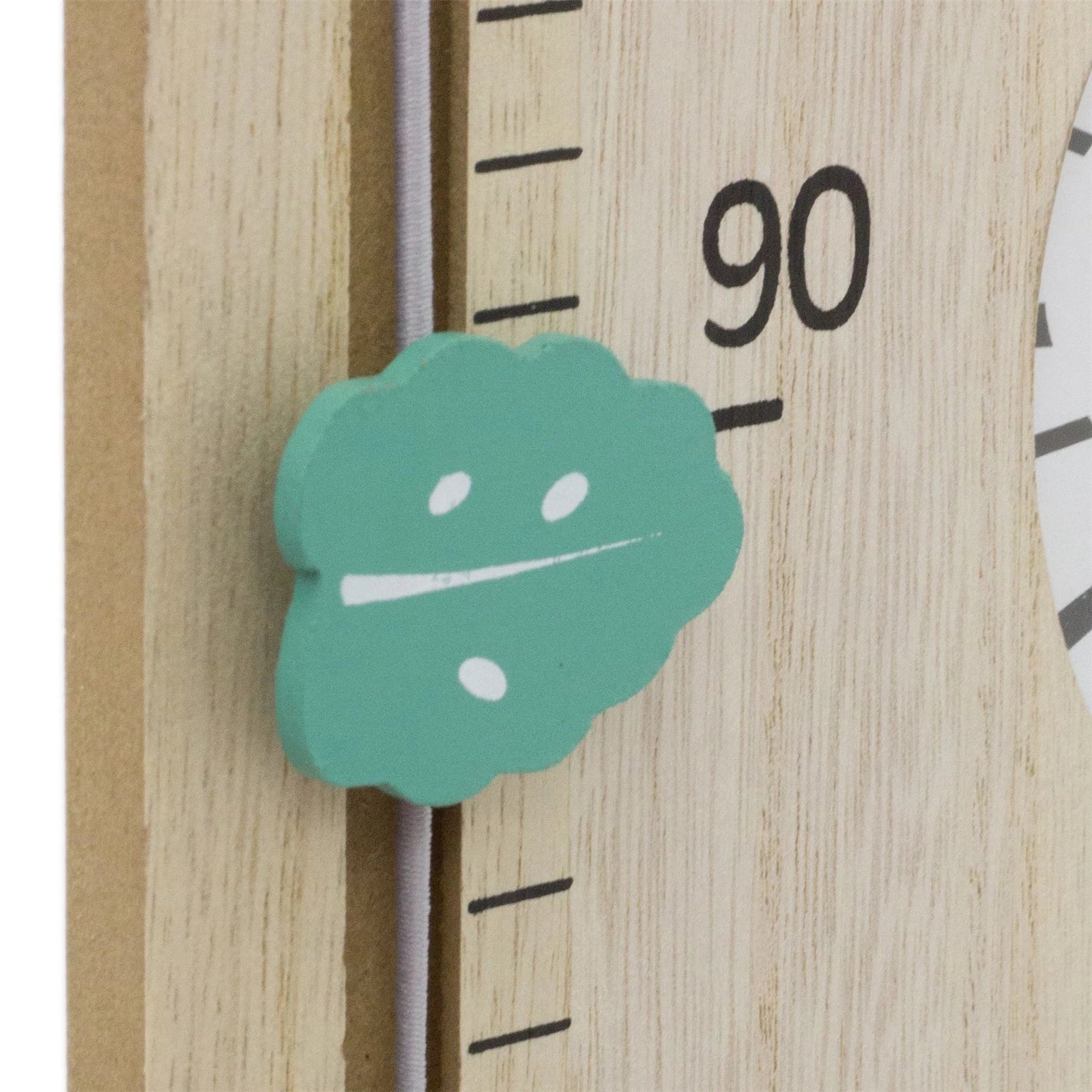 Teal leaf-shaped sticker on a wooden ruler with measurement markings